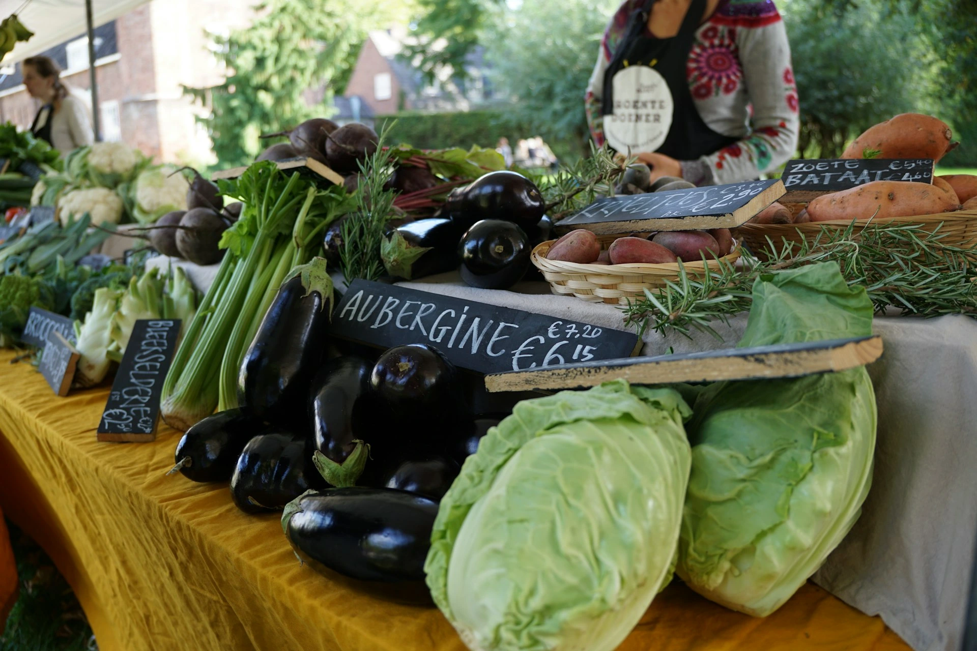 Fresh vegetables including aubergines, cabbage, and celery on a market stall table